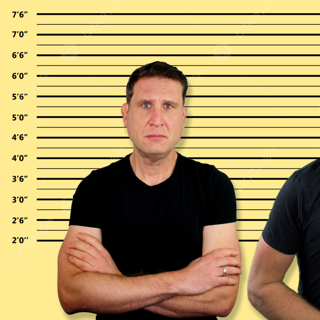 A man with a serious expression and arms crossed, wearing a black t-shirt, stands against a yellow background marked with a police lineup height chart, symbolizing the feeling of being criminalized or interrogated.