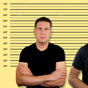 A man with a serious expression and arms crossed, wearing a black t-shirt, stands against a yellow background marked with a police lineup height chart, symbolizing the feeling of being criminalized or interrogated.